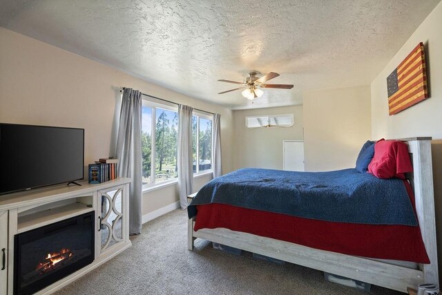 42640 Pinecone Ln, Auberry, CA 93602 - bedroom with a textured ceiling, a glass covered fireplace, carpet, baseboards, and ceiling fan