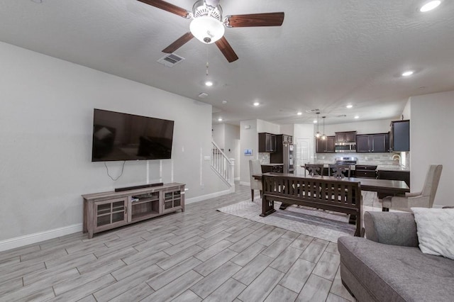 99 N Whittier Ave, Fresno, CA 93727 - living room with baseboards, light wood finished floors, stairway, and recessed lighting