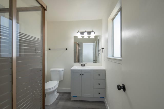 full bathroom featuring a shower stall, wood finished floors, toilet, baseboards, and vanity
