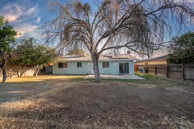 rear view of property featuring a fenced backyard, a patio area, stucco siding, a chimney, and solar panels