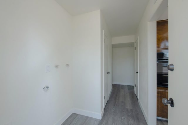 hall with light wood-style floors and baseboards