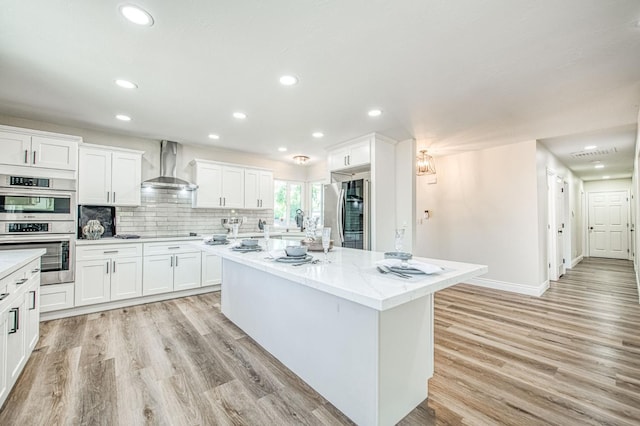 6117 N Colonial Ave, Fresno, CA 93704 - kitchen featuring stainless steel appliances, wall chimney exhaust hood, a kitchen island, light wood-style floors, and recessed lighting