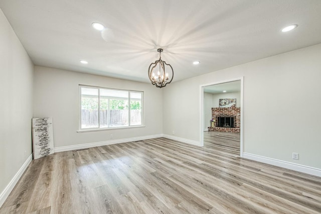 6117 N Colonial Ave, Fresno, CA 93704 - empty room featuring a chandelier, light wood-style flooring, baseboards, recessed lighting, and a brick fireplace