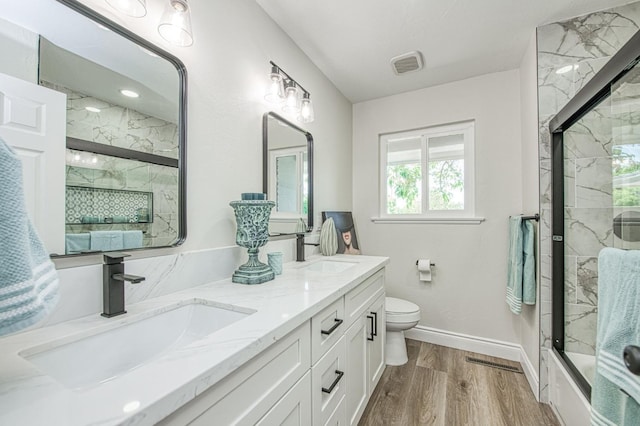 6117 N Colonial Ave, Fresno, CA 93704 - bathroom featuring a marble finish shower, wood finished floors, toilet, double vanity, and baseboards