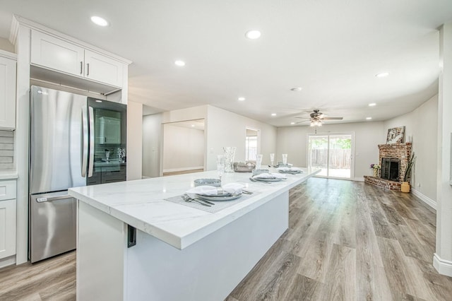 6117 N Colonial Ave, Fresno, CA 93704 - kitchen with freestanding refrigerator, a center island, ceiling fan, white cabinets, and light stone counters