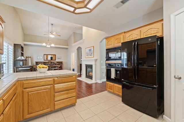 6423 N Bain Ave, Fresno, CA 93722 - kitchen with black appliances, arched walkways, open floor plan, a glass covered fireplace, and a peninsula