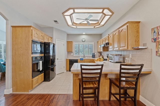 6423 N Bain Ave, Fresno, CA 93722 - kitchen featuring black appliances, a peninsula, ceiling fan, tile countertops, and backsplash