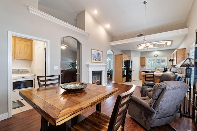 6423 N Bain Ave, Fresno, CA 93722 - living room with arched walkways, a glass covered fireplace, high vaulted ceiling, dark wood-style flooring, and washer / dryer