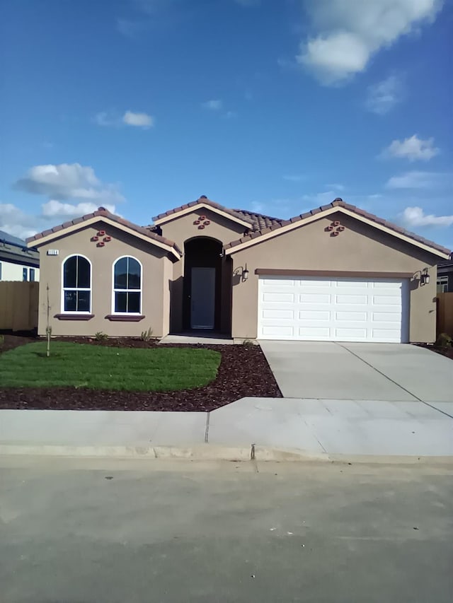 820 Shasta St, Madera, CA 93638 - mediterranean / spanish house with stucco siding, driveway, a tiled roof, a garage, and a front lawn