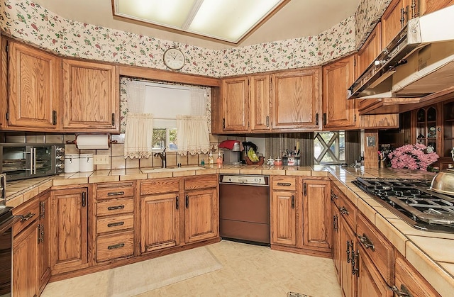 5082 N Maroa Ave, Fresno, CA 93704 - kitchen with tile counters, dishwashing machine, a sink, and brown cabinetry