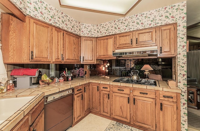 5082 N Maroa Ave, Fresno, CA 93704 - kitchen with dishwasher, under cabinet range hood, wallpapered walls, tile countertops, and gas stovetop