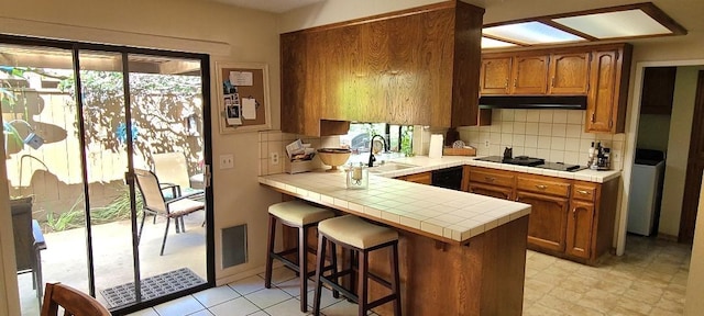 6300 N Palm Ave Unit 108, Fresno, CA 93710 - kitchen with black appliances, a sink, under cabinet range hood, tile counters, and a peninsula