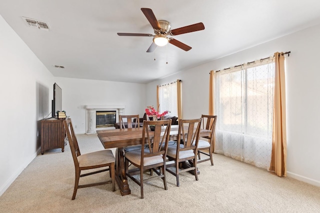 977 E Pennsylvania Ave, Fresno, CA 93720 - dining room featuring light carpet, a ceiling fan, a glass covered fireplace, and baseboards