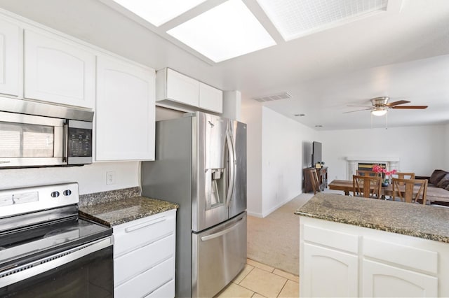 977 E Pennsylvania Ave, Fresno, CA 93720 - kitchen with stainless steel appliances, light carpet, ceiling fan, and white cabinetry