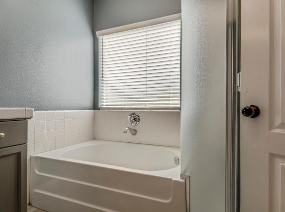 full bath featuring a bath and a textured wall