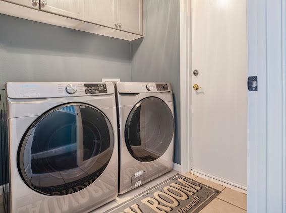 washroom featuring cabinet space, washing machine and clothes dryer, and tile patterned flooring
