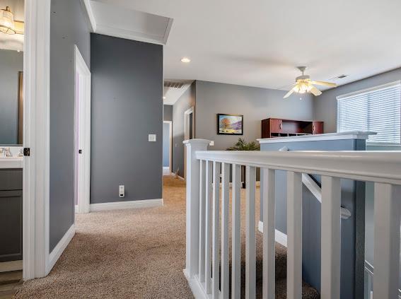 corridor featuring carpet floors, baseboards, recessed lighting, and an upstairs landing