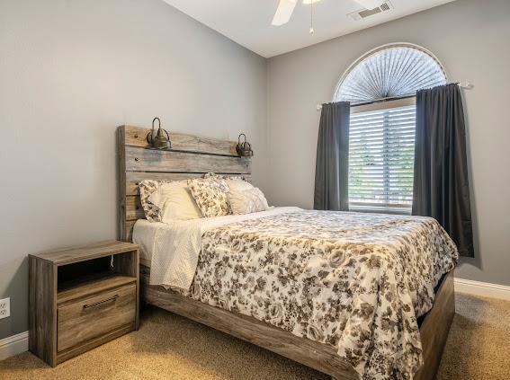 bedroom featuring light carpet, baseboards, and a ceiling fan