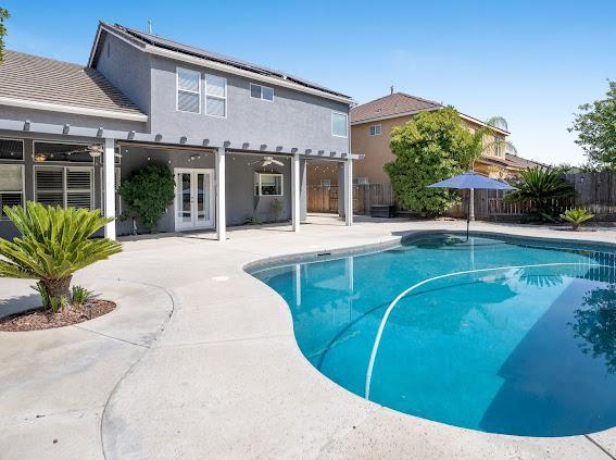 view of swimming pool with french doors, a fenced backyard, and a patio area