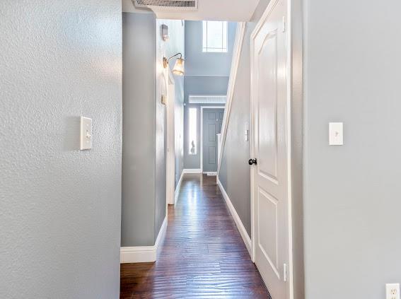 hallway with baseboards, dark wood-type flooring, and a textured wall