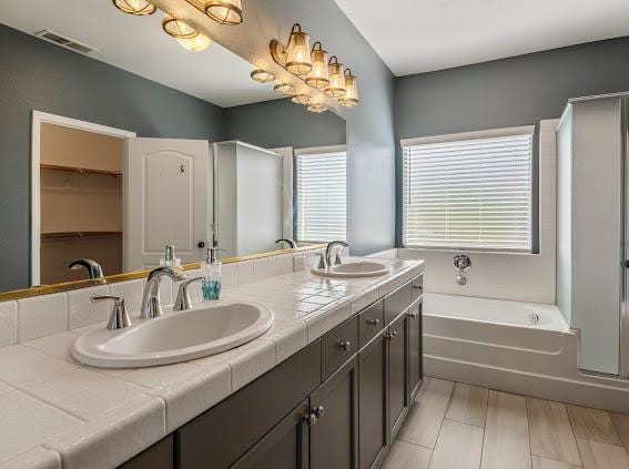 full bathroom featuring double vanity, a bath, and an enclosed shower