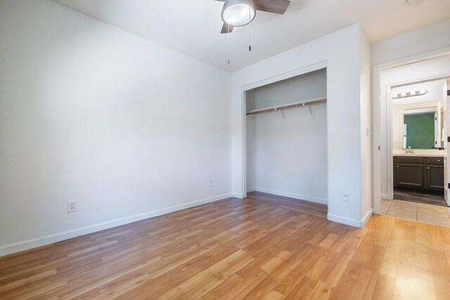 unfurnished bedroom with light wood-style flooring, a closet, baseboards, and ceiling fan