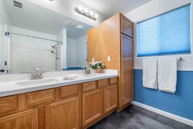 full bath with a tile shower, baseboards, and double vanity