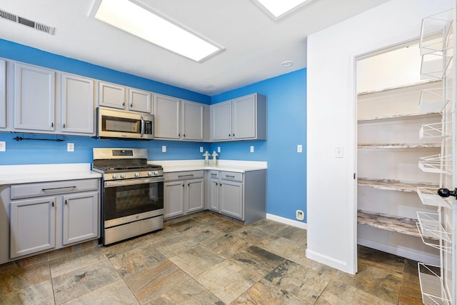 6254 E Bellaire Way, Fresno, CA 93727 - kitchen with stainless steel appliances, gray cabinetry, light countertops, and stone finish flooring
