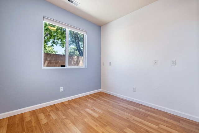 spare room with baseboards and light wood-style floors