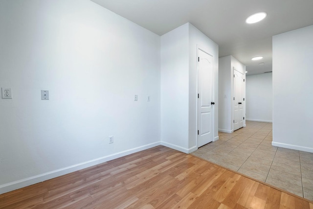 unfurnished room with light wood-type flooring and baseboards