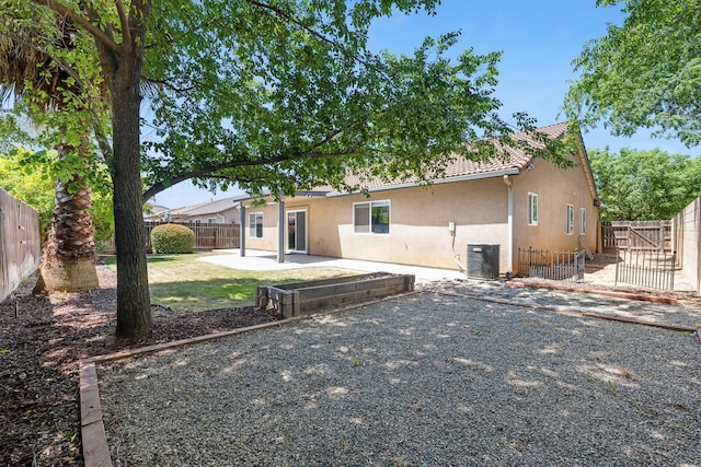 rear view of house with stucco siding, a fenced backyard, and a patio