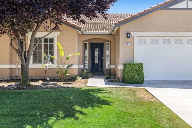 property entrance featuring stucco siding, a garage, a lawn, and a tiled roof