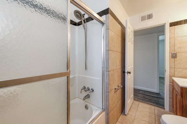 5535 N Millbrook Ave, Fresno, CA 93710 - bathroom with tile patterned floors, shower / bath combination with glass door, vanity, tile walls, and toilet