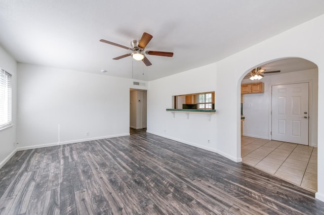 5535 N Millbrook Ave, Fresno, CA 93710 - unfurnished living room featuring arched walkways, ceiling fan, wood finished floors, and baseboards