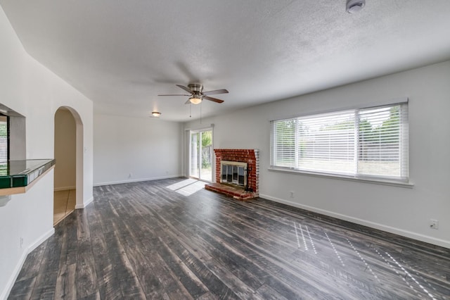 5535 N Millbrook Ave, Fresno, CA 93710 - unfurnished living room featuring a ceiling fan, dark wood-style floors, a brick fireplace, baseboards, and a textured ceiling