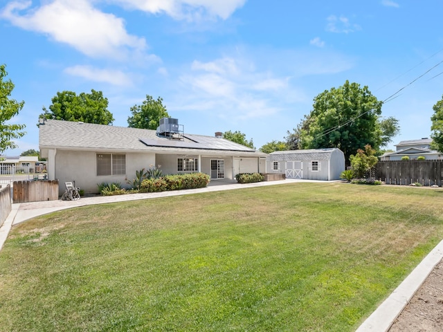 ranch-style home featuring roof mounted solar panels, a shed, stucco siding, and an outbuilding