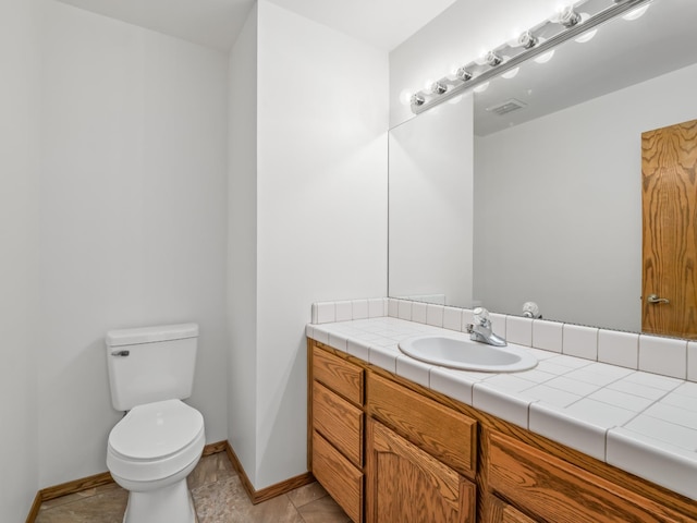 half bathroom featuring toilet, baseboards, and vanity