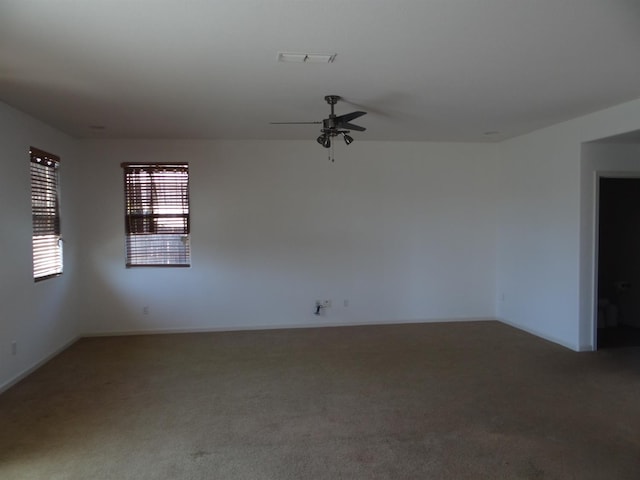 carpeted spare room featuring a ceiling fan and baseboards