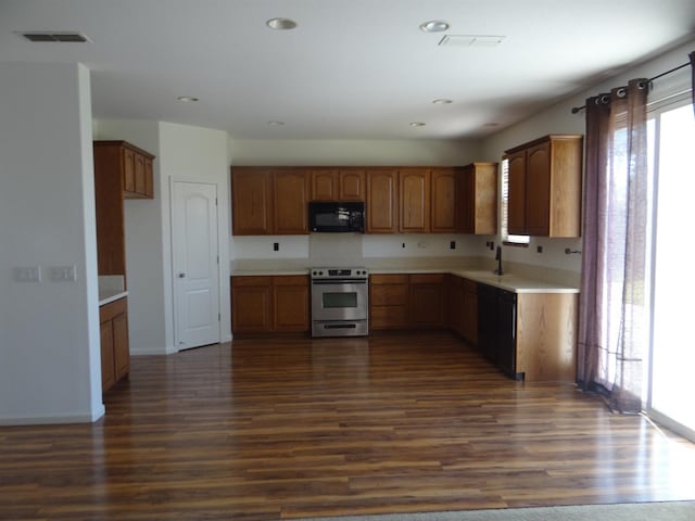 kitchen featuring black microwave, stainless steel range with electric stovetop, dark wood-style floors, light countertops, and recessed lighting