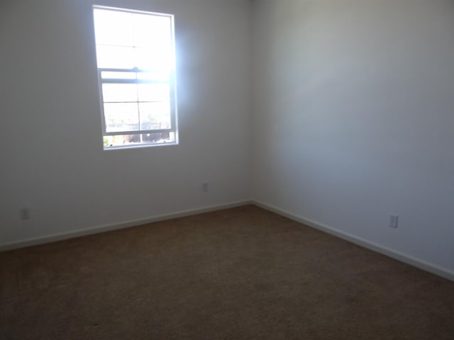 unfurnished room with carpet and baseboards