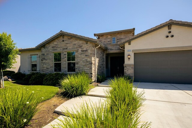 3636 Elberta Cir, Dinuba, CA 93618 - view of front of home with stone siding, an attached garage, driveway, and stucco siding