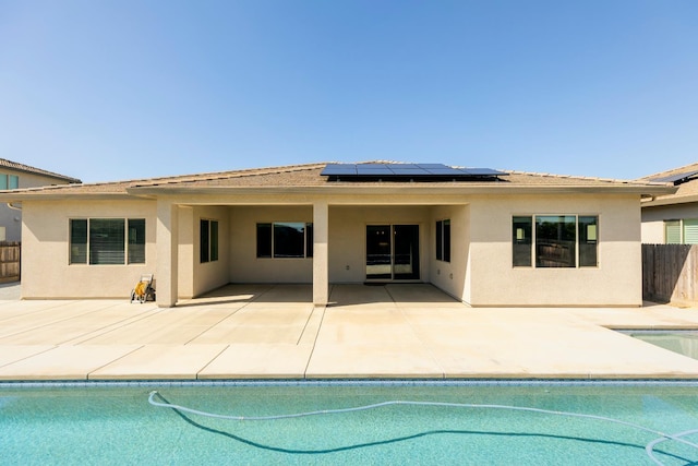 3636 Elberta Cir, Dinuba, CA 93618 - back of property with stucco siding, solar panels, an outdoor pool, and fence