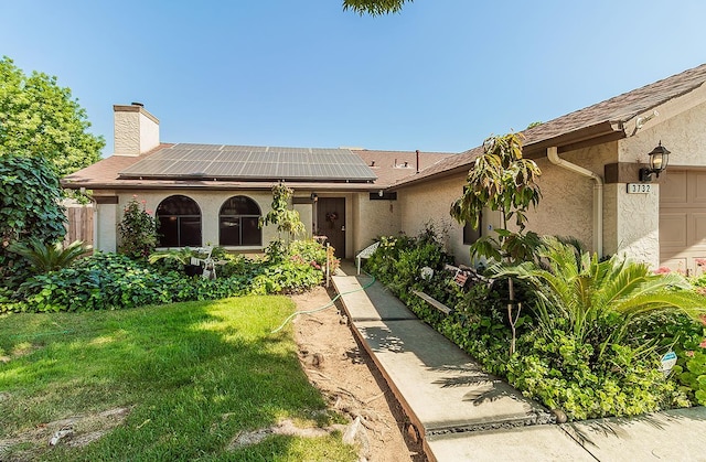 3732 W Garland Ave, Fresno, CA 93722 - ranch-style home featuring stucco siding, a chimney, solar panels, and a garage