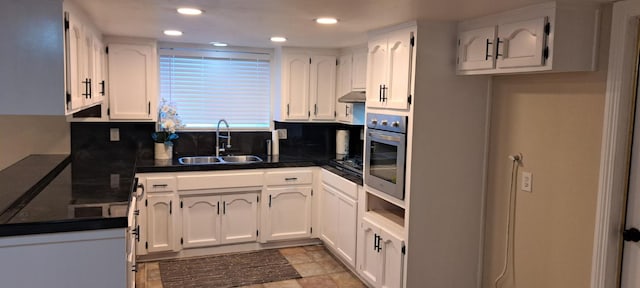 1690 W Wall Ln, Porterville, CA 93257 - kitchen with a sink, dark countertops, stainless steel oven, white cabinets, and under cabinet range hood