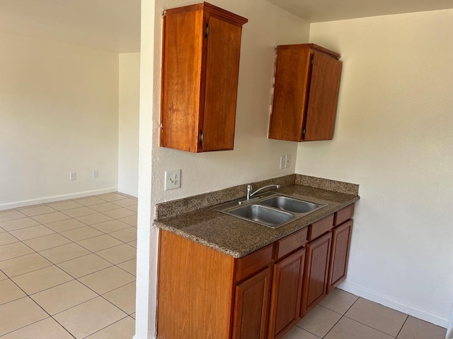 2645 W Robinson Ave, Fresno, CA 93705 - kitchen with a sink, light tile patterned floors, dark countertops, baseboards, and brown cabinets