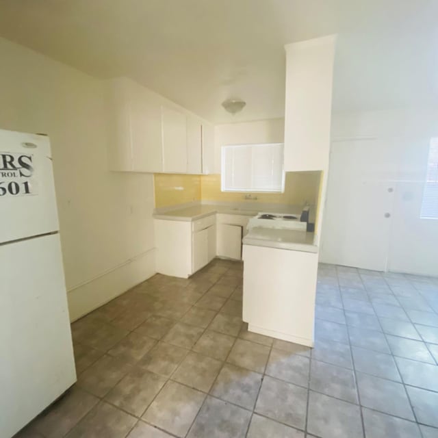 408 S Woodrow Ave, Fresno, CA 93702 - kitchen featuring freestanding refrigerator, light tile patterned floors, white cabinetry, and light countertops