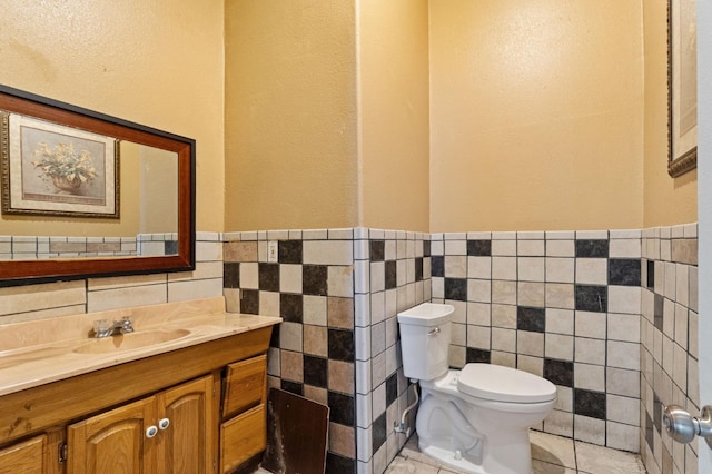 900 Sonora St, Madera, CA 93638 - half bath with tile walls, toilet, vanity, a wainscoted wall, and a textured wall