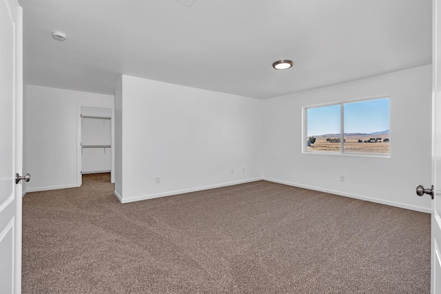 empty room featuring carpet floors, baseboards, and a smoke detector