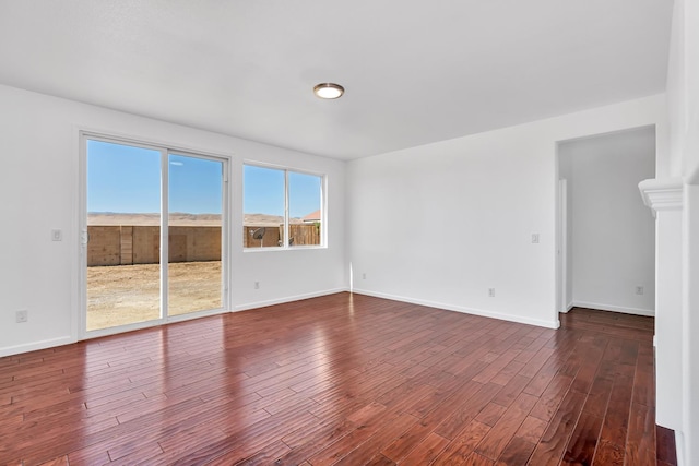 empty room featuring dark wood-type flooring and baseboards