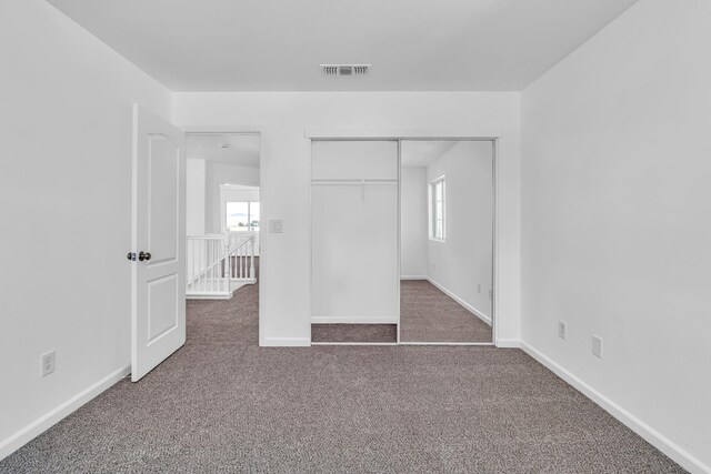 unfurnished bedroom with carpet floors, baseboards, and a closet